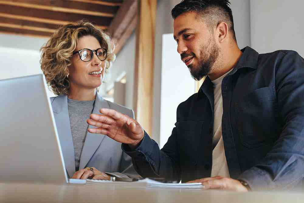 Recruiter and employee reviewing paperwork and documents on laptop